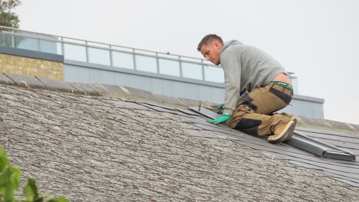 Couvreur en train de poser des tuiles, rénovation de toiture à Reims