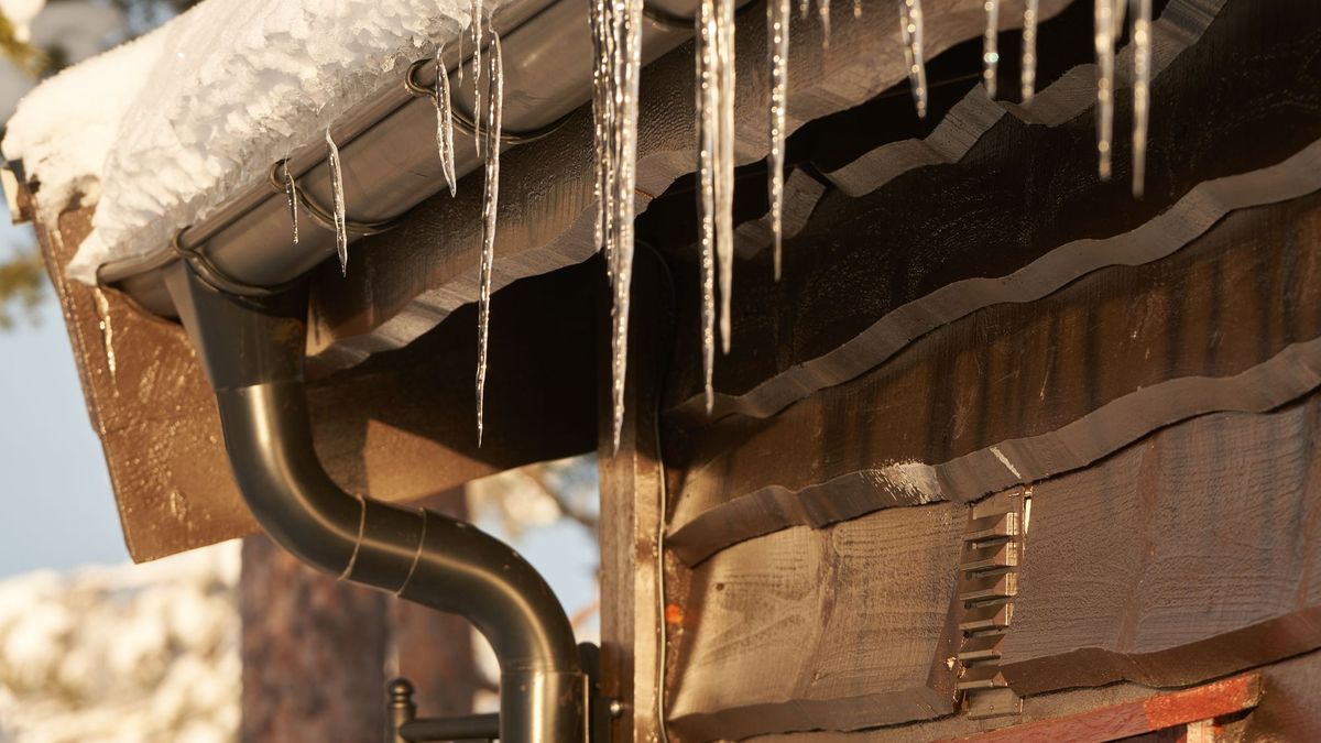 Stalactites de glace sur une gouttière en hiver, rénovation de toiture à Colmar